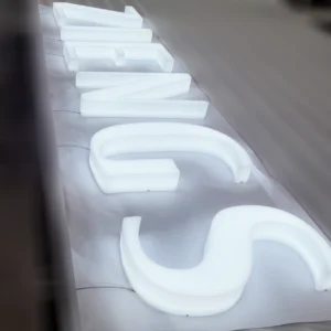 A close-up photo of a full lit acrylic letter. The photo shows a channel letter sign made of white acrylic and lit with white LEDs.